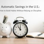 Cover image about automatic savings in the U.S.: a white piggy bank with a rolled U.S. dollar bill, a classic alarm clock showing time, and an open notebook with a pen on a wooden desk—symbolizing saving routines, automation, and habit-building without relying on discipline.